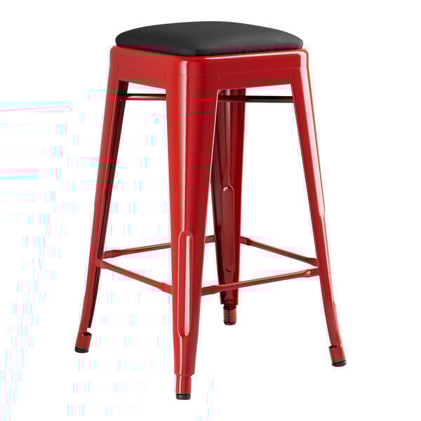 A red Lancaster Table & Seating backless counter height stool with black cushion.
