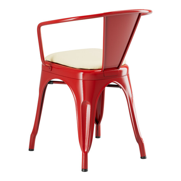A red Lancaster Table & Seating metal arm chair with a white cushion.