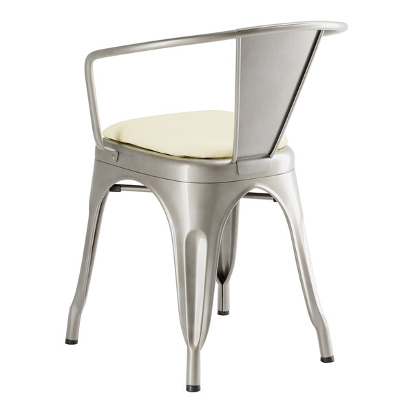 A Lancaster Table & Seating metal arm chair with a white cushion.