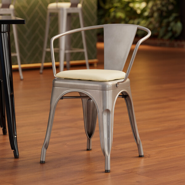 A Lancaster Table & Seating metal arm chair with a white cushion.