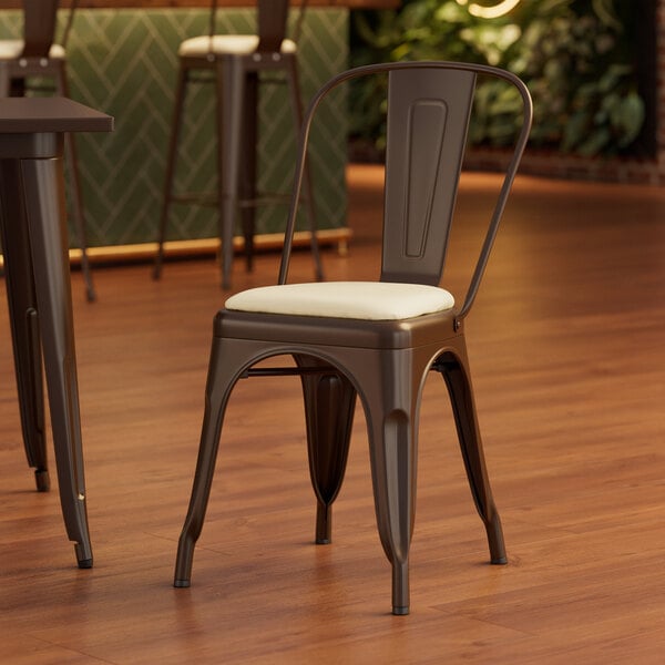 A Lancaster Table & Seating brown metal cafe chair with a white cushion.