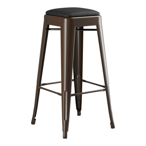 A brown metal Lancaster Table & Seating backless bar stool with a black cushioned seat.