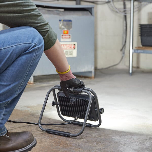 A man using a Genesis LED work light to fix a tool.