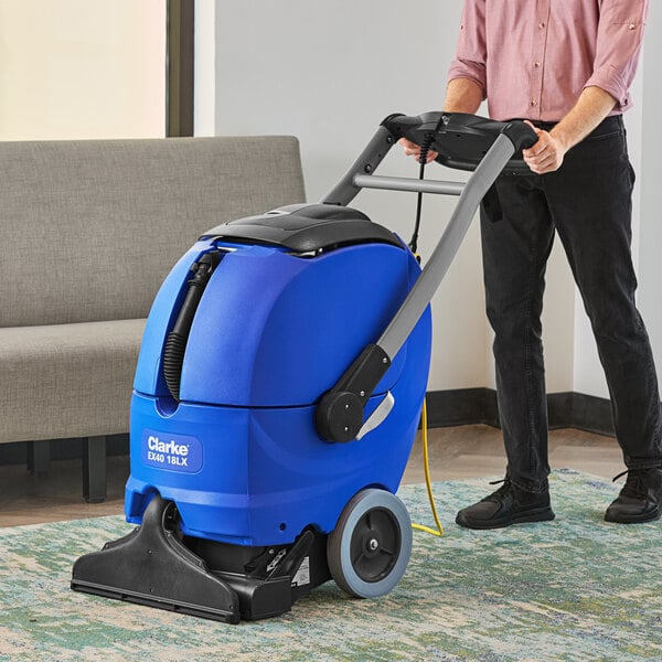 A person using a Clarke blue carpet extractor to clean a rug.