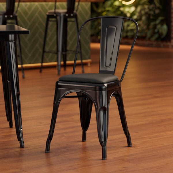 A Lancaster Table & Seating black metal cafe chair with black vinyl cushion.