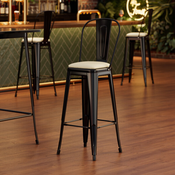 A Lancaster Table & Seating black barstool with a white cushion.