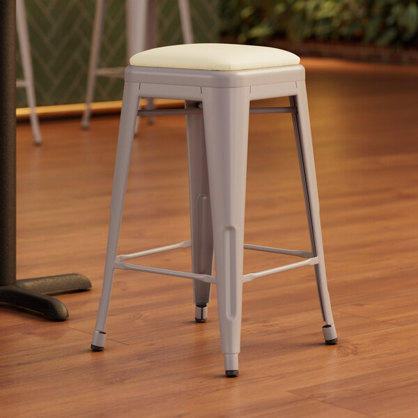 A gray Lancaster Table & Seating backless counter height stool with a white cushion.