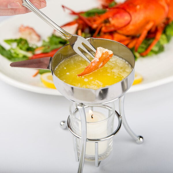 A person using a fork to dip lobster in a Thunder Group butter melter.