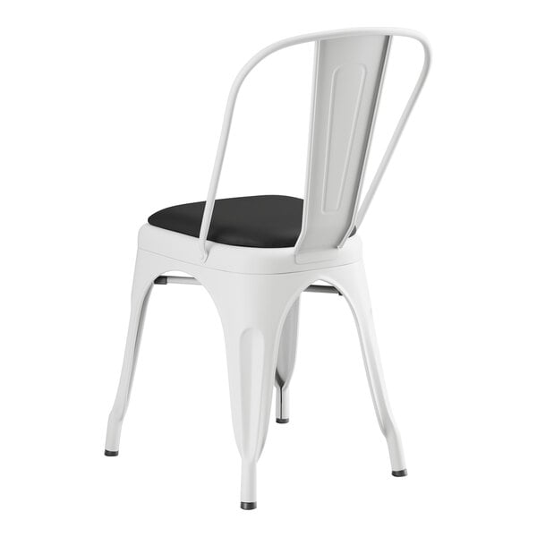 A Lancaster Table & Seating white metal cafe chair with black cushion.