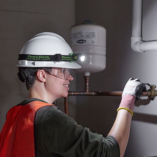 worker fixing an old pipe wearing a head lamp