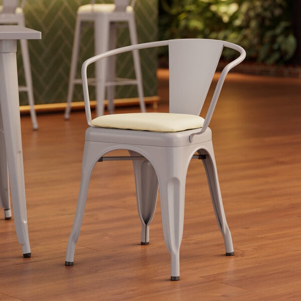 A Lancaster Table & Seating nickel gray metal arm chair with a white cushion.