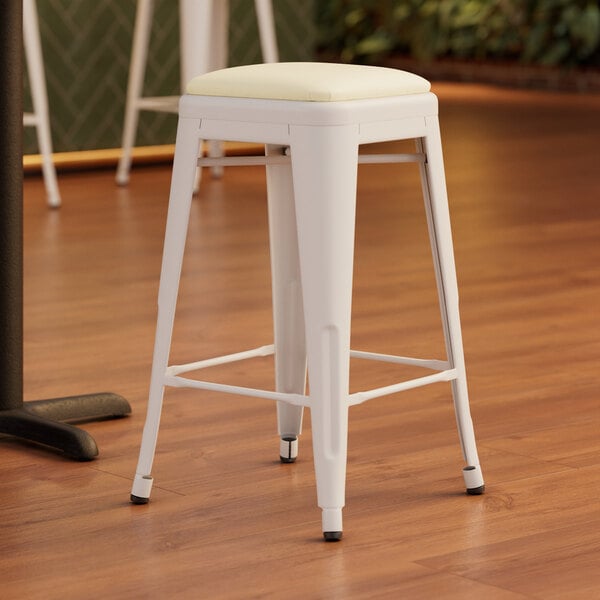 A white Lancaster Table & Seating backless counter height stool with a white cushion on top.