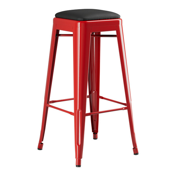 A Lancaster Table & Seating red metal backless barstool with a black cushion.