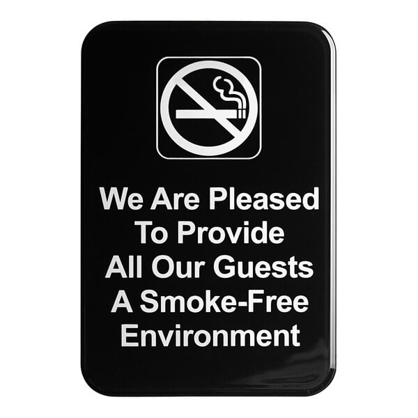 A black sign with white text that says "We Are Pleased To Provide All Our Guests A Smoke-Free Environment"