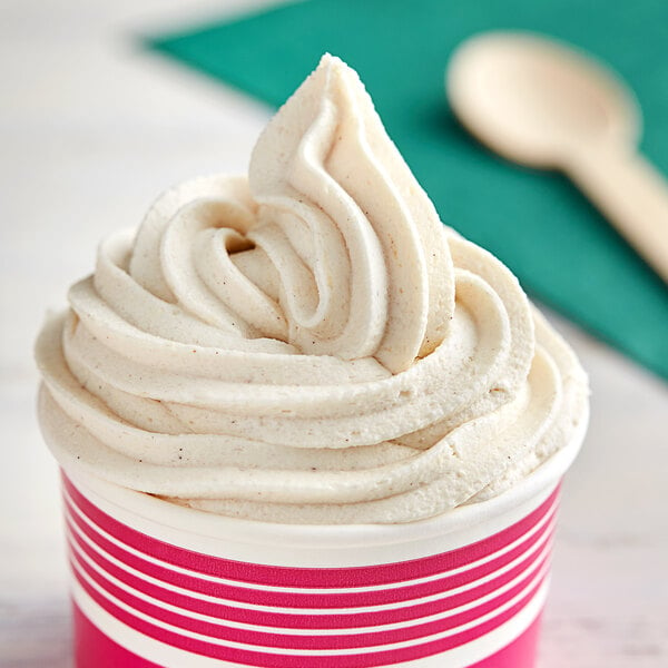 A close-up of a cup of white horchata soft serve with a spoon on top.