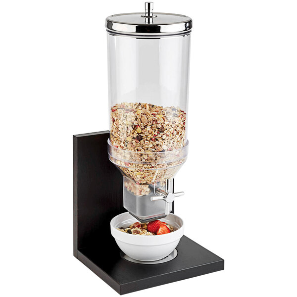 An APS Bridge cereal dispenser filled with cereal with a bowl of strawberries on top.