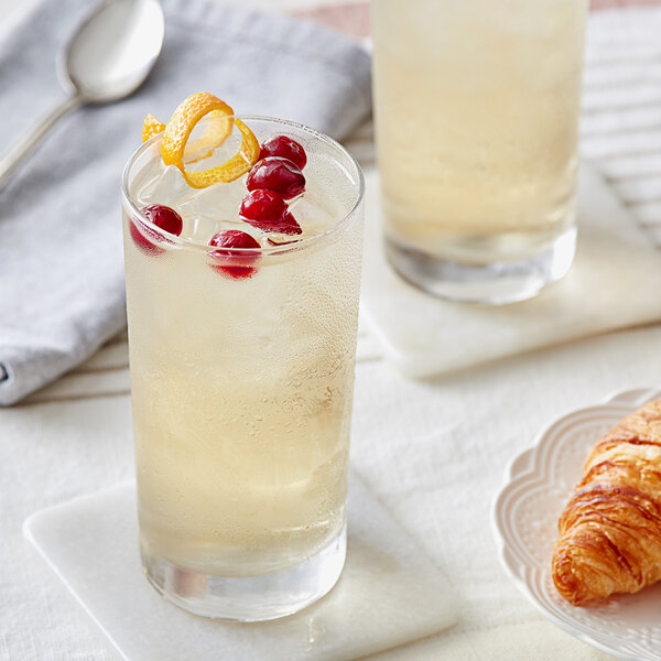 A glass of Davidson's Organic Cranberry Orange Iced Tea with ice and cherries.