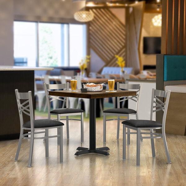 A Lancaster Table & Seating butcher block table with a basket of food and four chairs.