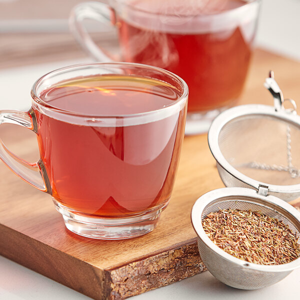 A glass cup of Davidson's Organic Red and Green Herbal Loose Leaf Tea on a cutting board.