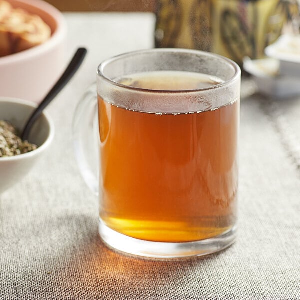 A glass mug of Davidson's Organic Guayusa tea on a table next to food.