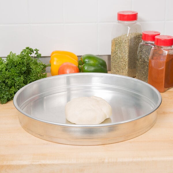 A pizza dough in an American Metalcraft aluminum cake pan.