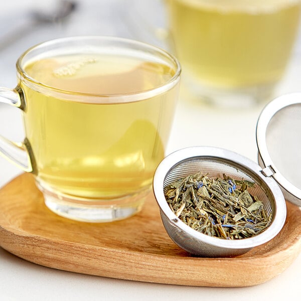 A strainer filled with Davidson's Organic Green Leaves over a glass of liquid.