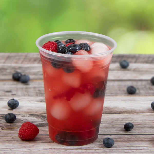 A Solo Ultra Clear plastic cup filled with fruit juice, ice, and berries.