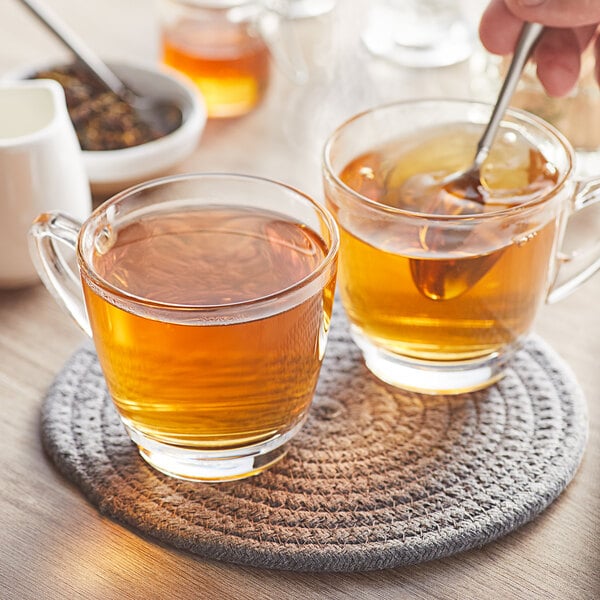 A glass cup of Davidson's Organic Sun, Moon, and Stars loose leaf tea with a spoon in it.