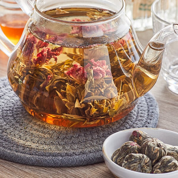 A glass teapot with Davidson's Organic Spring Cup Tea Blooms in liquid.