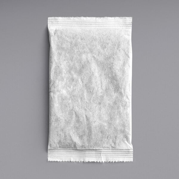 A white paper bag with Davidson's Organic Ginger Peach Iced Tea Filter Packs on a gray surface.