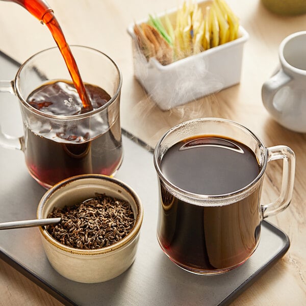 A white cup of Davidson's Organic Pu-erh Black tea on a saucer with a spoon.