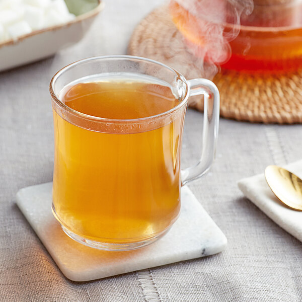 A glass mug of Davidson's Organic Cacao Bliss loose leaf tea on a marble coaster.