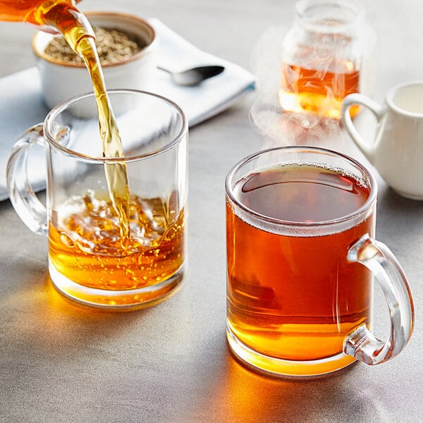 A person pouring Davidson's Organic Decaf Green Loose Leaf Tea into a glass mug.