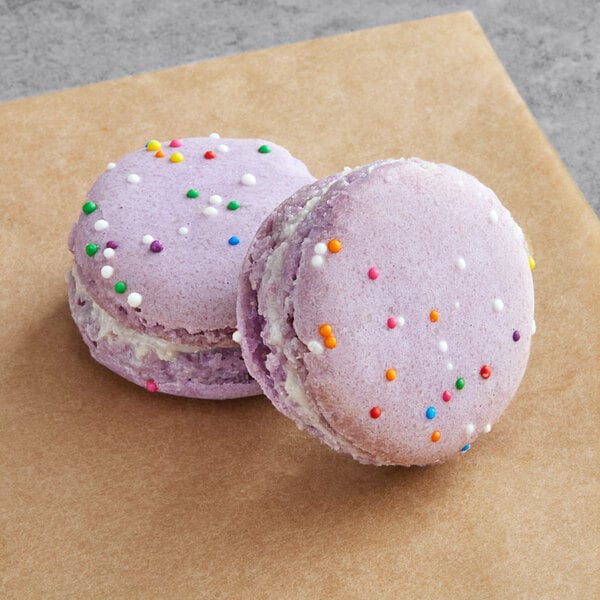 Two purple Macaron Centrale macarons with sprinkles on top.