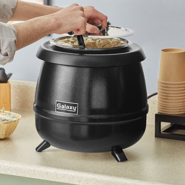 A person using the Galaxy Soup Kettle Warmer to cook food.