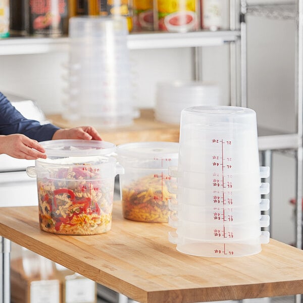 A woman using a Vigor translucent round polypropylene food storage container to hold food.