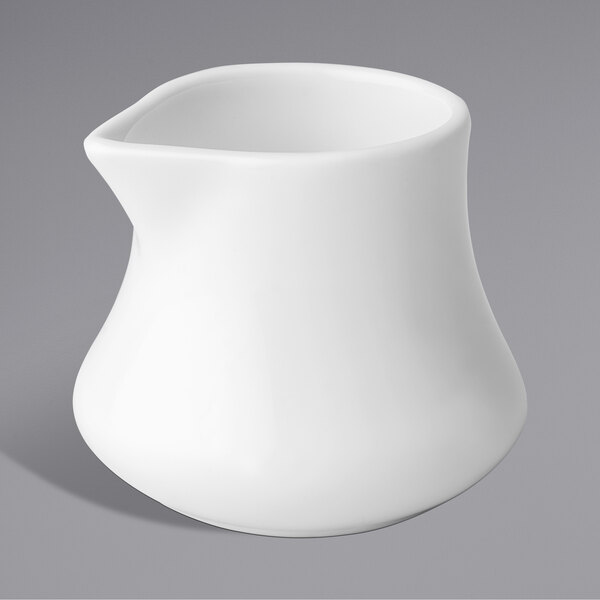 A Chef & Sommelier white china creamer with a curved shape and handle.