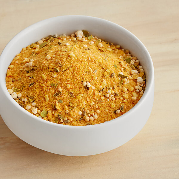 A bowl of Ball Kosher Dill Pickle Mix powder on a wooden table.