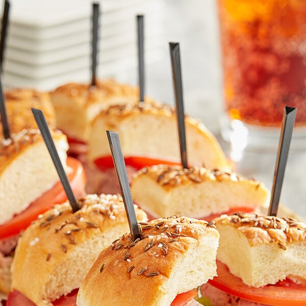 A plate of sandwiches with black plastic prism food picks.