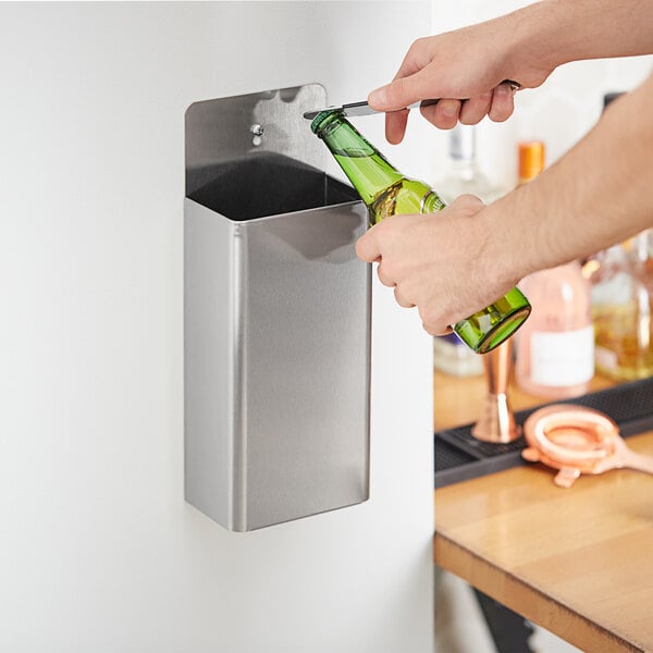 A person using a Choice stainless steel bottle cap catcher to open a bottle of beer.