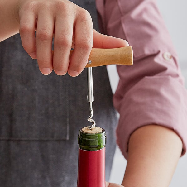 A person using an Acopa T-Style corkscrew with a wood handle to open a wine bottle.