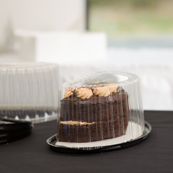 Half-round plastic cake container with a black base holding half of a chocolate cake