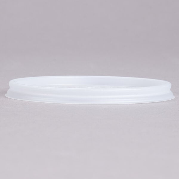 A translucent plastic lid with a straw slot on a white surface.