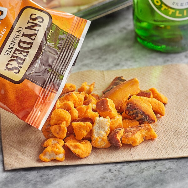 A bag of Snyder's of Hanover Cheddar Cheese Pretzel Pieces on a table in a stadium concession stand.