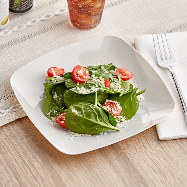 A Fineline plastic salad plate with salad, tomatoes, and cheese.