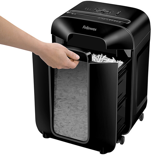 A hand using a Fellowes Powershred LX85 paper shredder.
