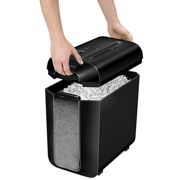 A hand using a Fellowes Powershred LX65 paper shredder to shred paper.