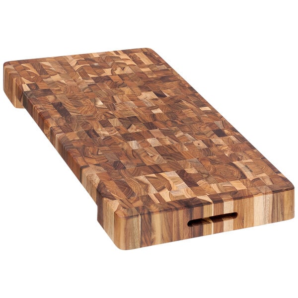 A Teakhaus end grain teakwood cutting board with hand grips.