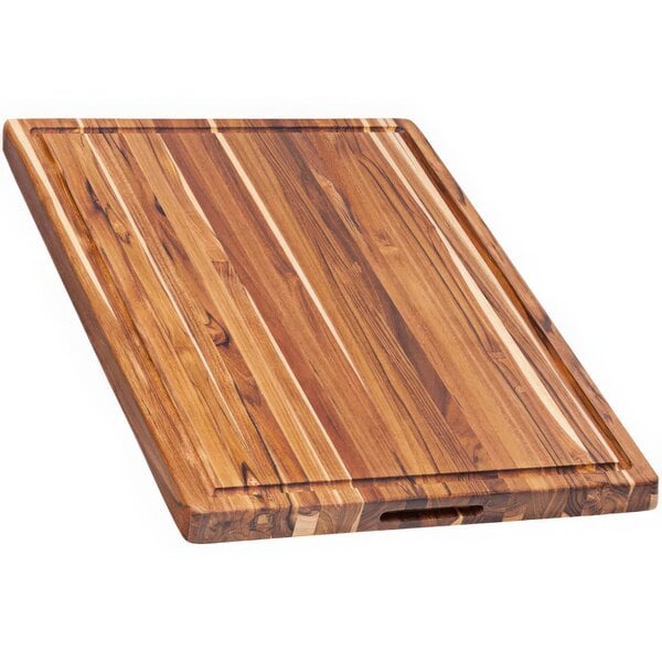 A Teakhaus edge grain teakwood cutting board with hand grips.