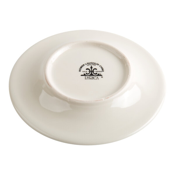 A white ceramic saucer is shown upside down, displaying a manufacturer's mark and logo on the bottom.